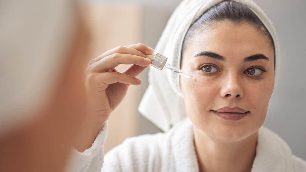 A woman putting serum on face after bath