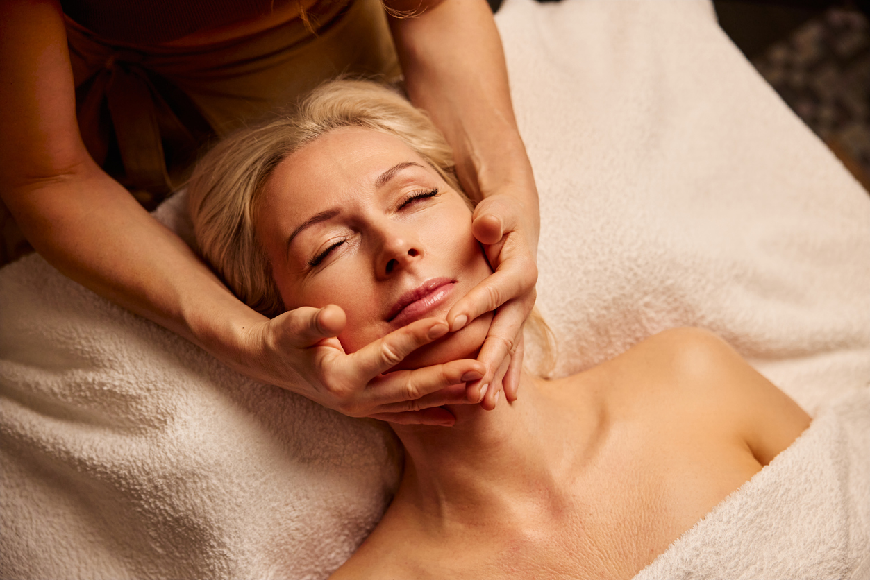 a woman receiving a facial massage at a spa